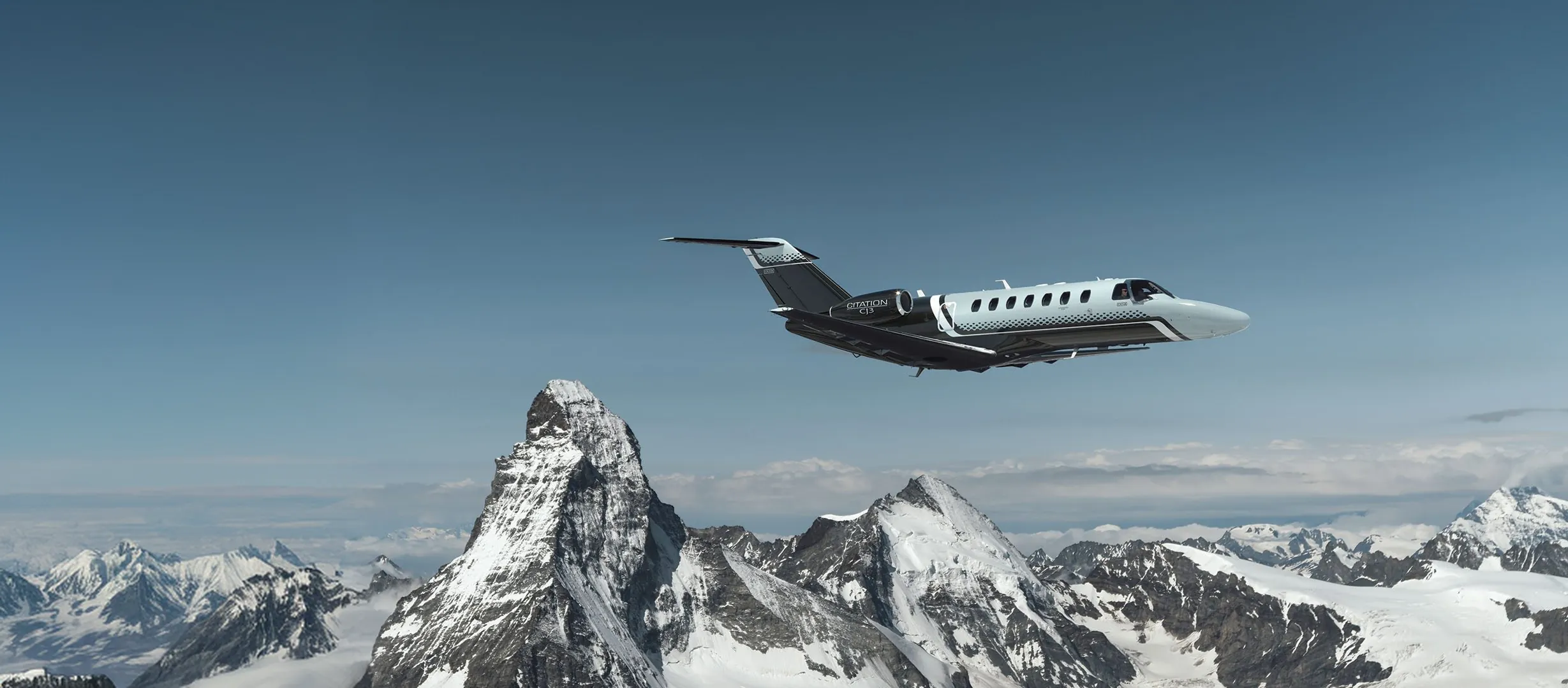 Light jet privado volando sobre montañas nevadas