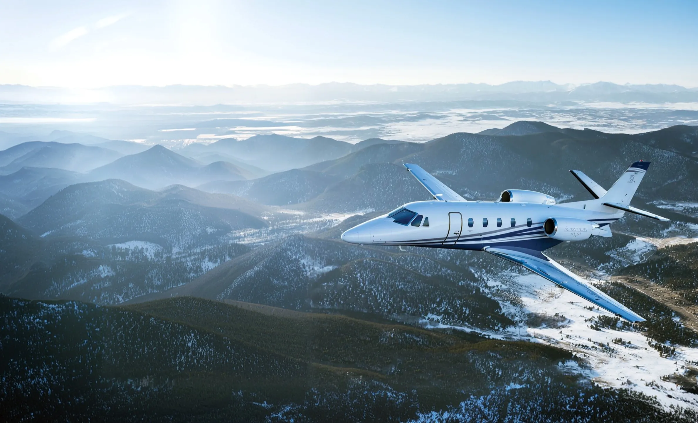 Super light jet privado volando sobre montañas boscosas salpicadas de nieve