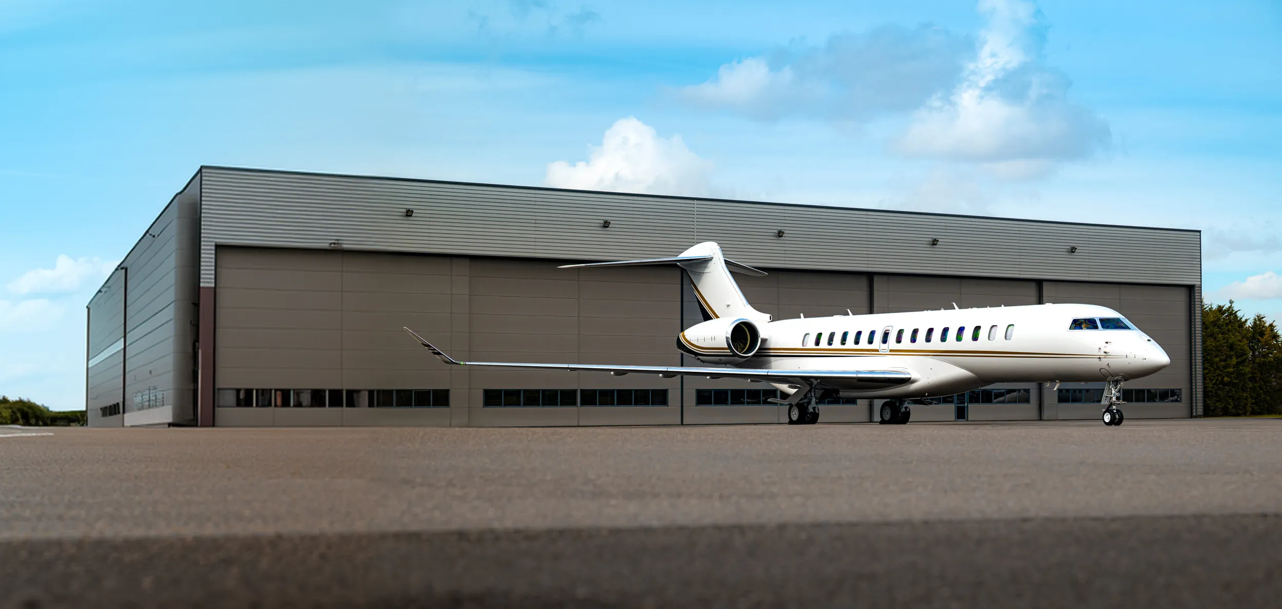 Jet privado de ultralargo alcance aparcado en la plataforma frente a un hangar