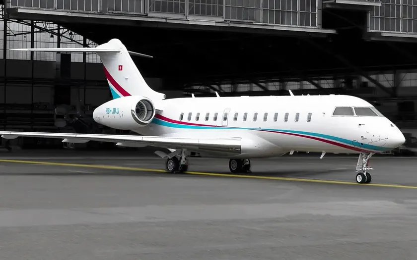Jet privado Bombardier Global 5500 aparcado en la plataforma frente a un hangar abierto