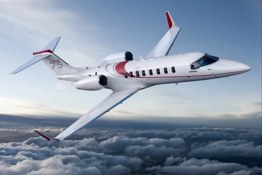 Jet privato Bombardier Learjet 75 in volo sopra le nuvole, bianco con finiture rosse