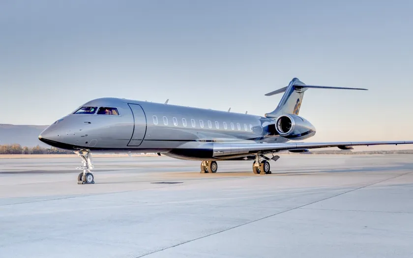 Jet privado Bombardier Global 6000 aparcado en una plataforma despejada al amanecer, con colinas a lo lejos
