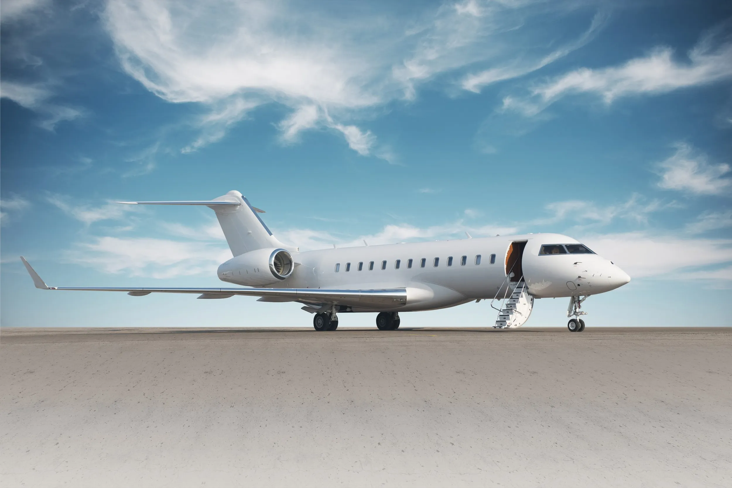 Un jet privado Bombardier Global con la escalerilla desplegada en la plataforma bajo un cielo azul