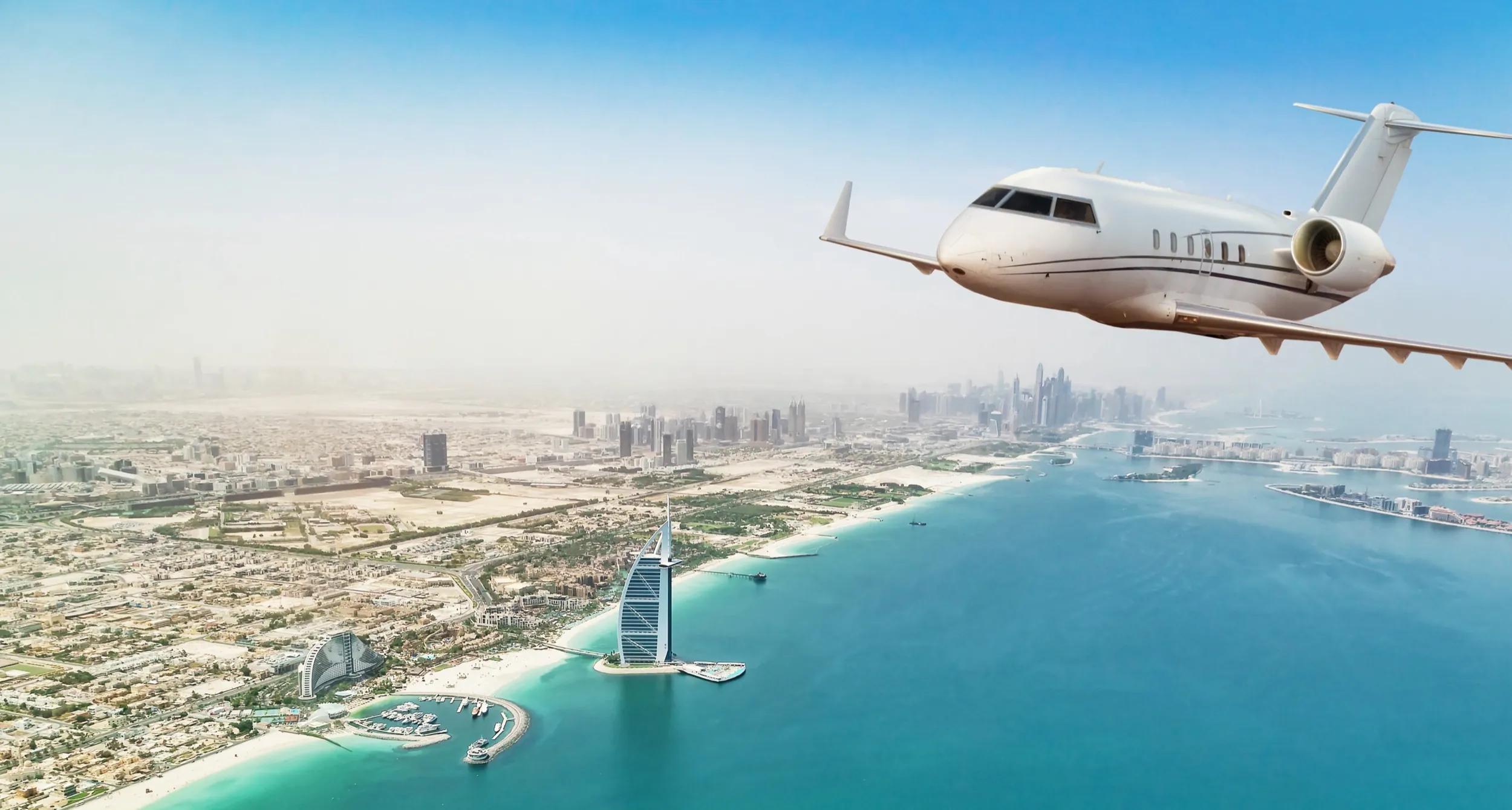 Un jet privado en vuelo sobre la costa de Dubái y el Burj Al Arab