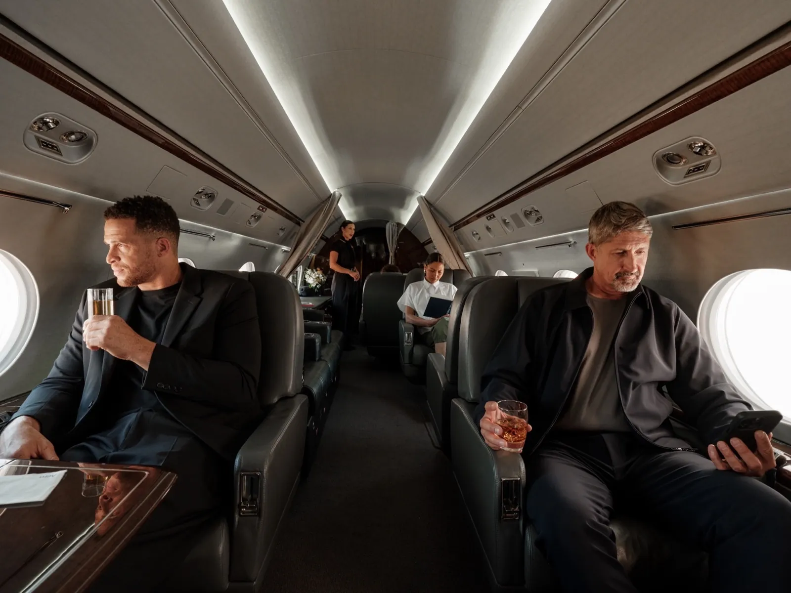 Pasajeros relajándose con una copa en la cabina de un jet privado