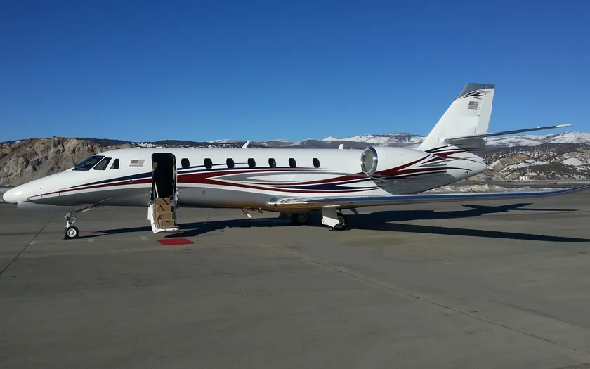 Jet privado Cessna Citation Sovereign+ estacionado en la plataforma con montañas nevadas al fondo