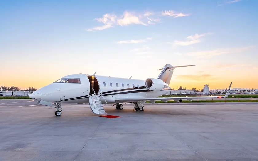 Jet privado Bombardier Challenger 650 aparcado al atardecer con la escalerilla desplegada sobre una alfombra roja