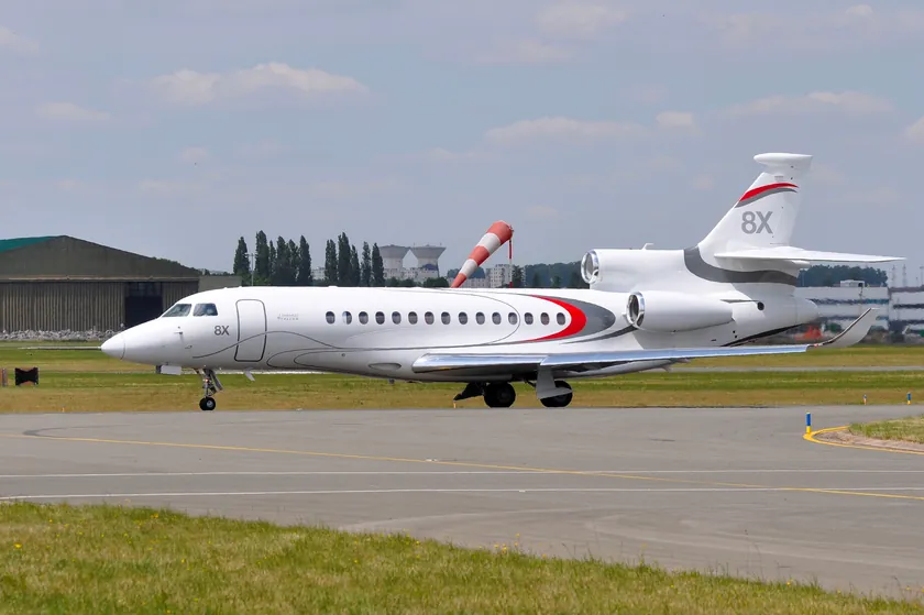 Jet privado Dassault Falcon 8X rodando junto a un hangar con una manga de viento al fondo