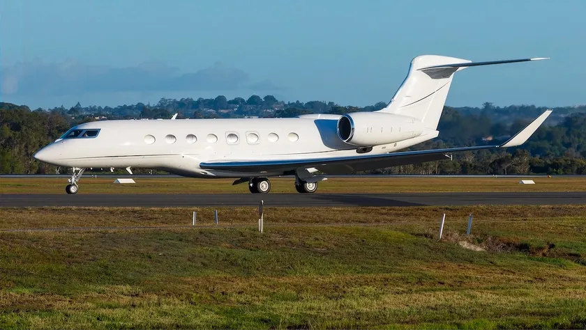 Jet privado Gulfstream G650ER en la pista con colinas verdes al fondo