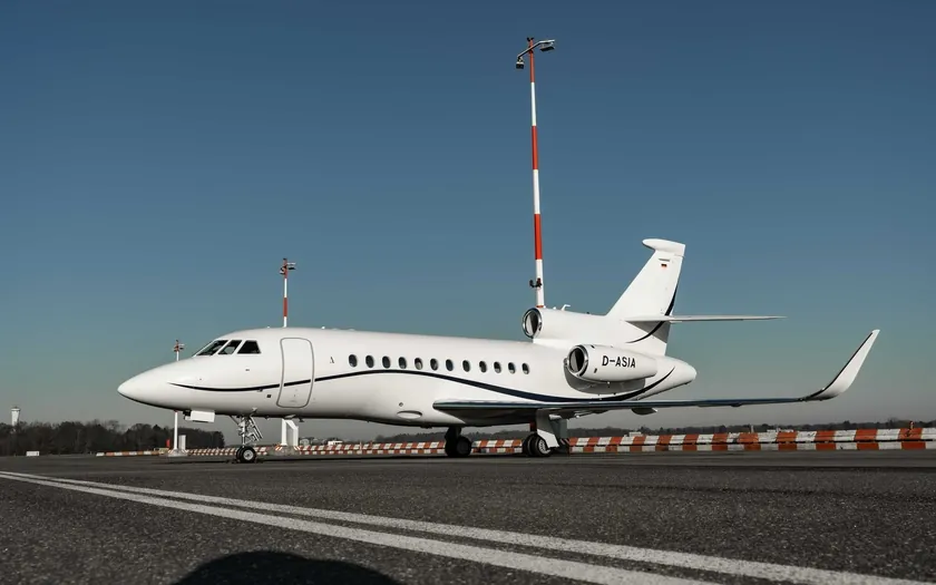 Jet privado Dassault Falcon 900LX en la pista, visto de perfil contra un cielo azul despejado