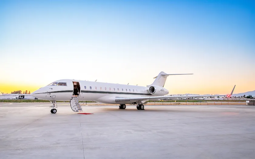 Jet privado Bombardier Global 6500 aparcado en la pista al atardecer, con escalerilla de embarque y alfombra roja