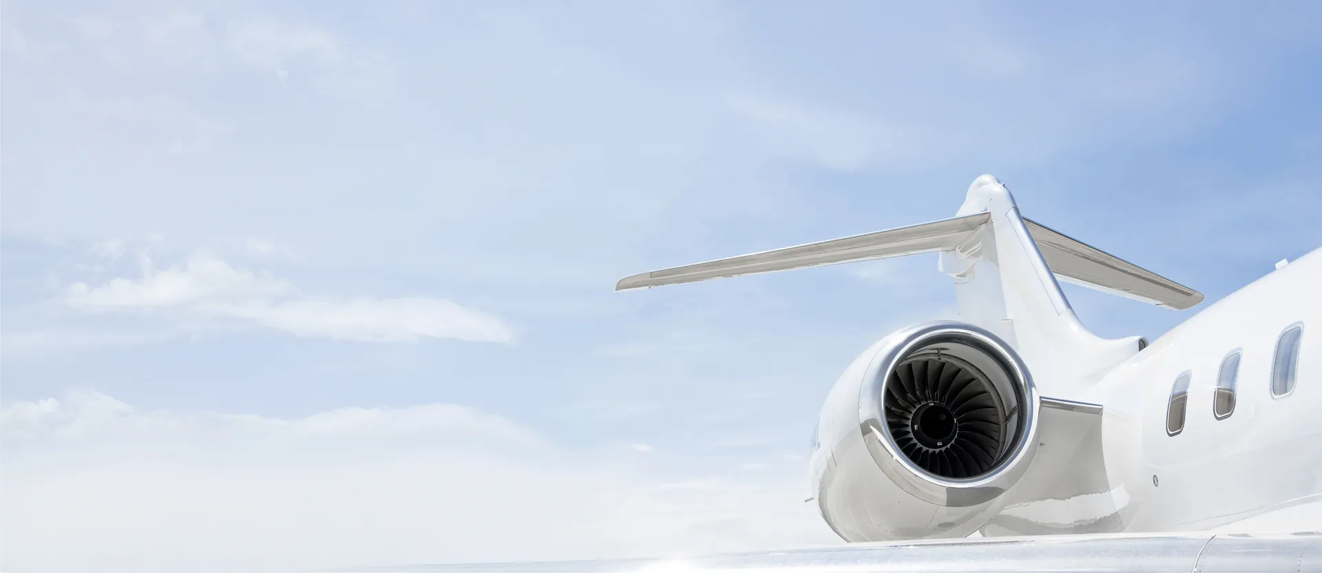Primer plano del motor y el ala de un jet privado contra un cielo azul