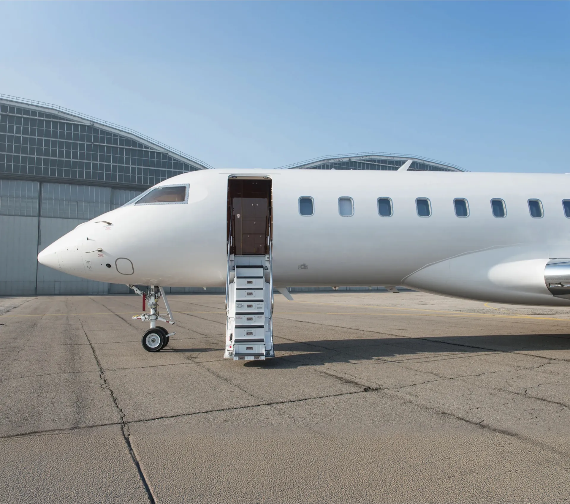 Un jet privado estacionado frente a un hangar con la escalerilla desplegada