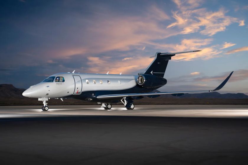 Embraer Praetor 500 private jet parked on the apron at dusk with mountains in the background