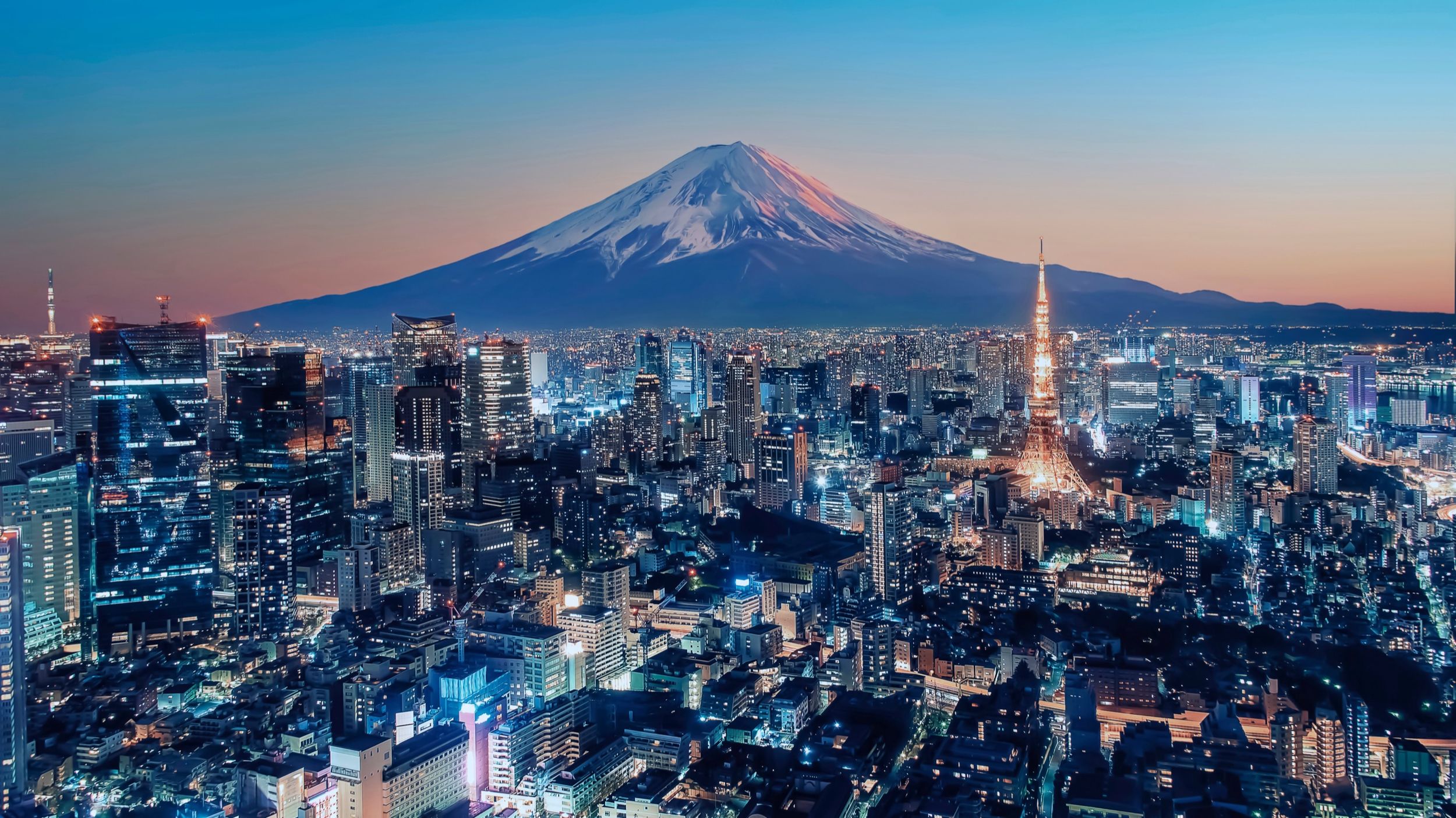 Tokyo Tower and the city skyline with Mount Fuji in the distance at dusk