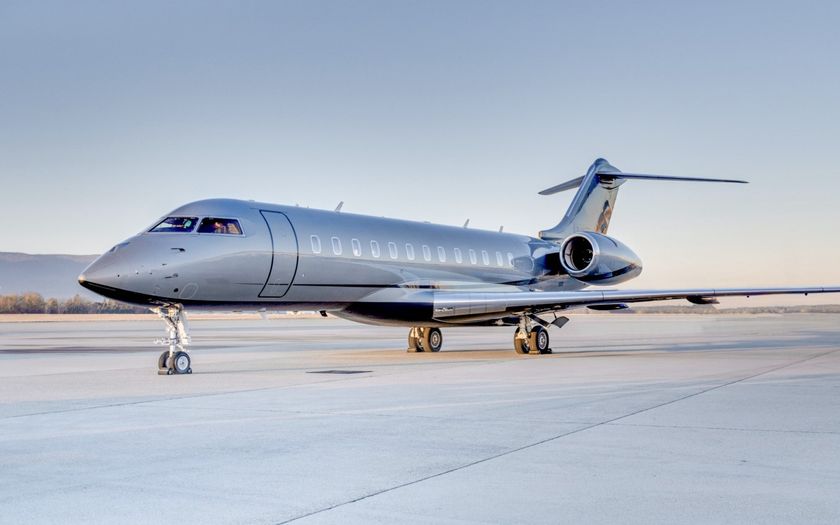 Bombardier Global 6000 private jet parked on an open ramp at dawn with hills in the distance