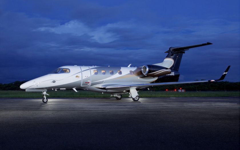 Embraer Phenom 300E private jet parked on the tarmac at dusk