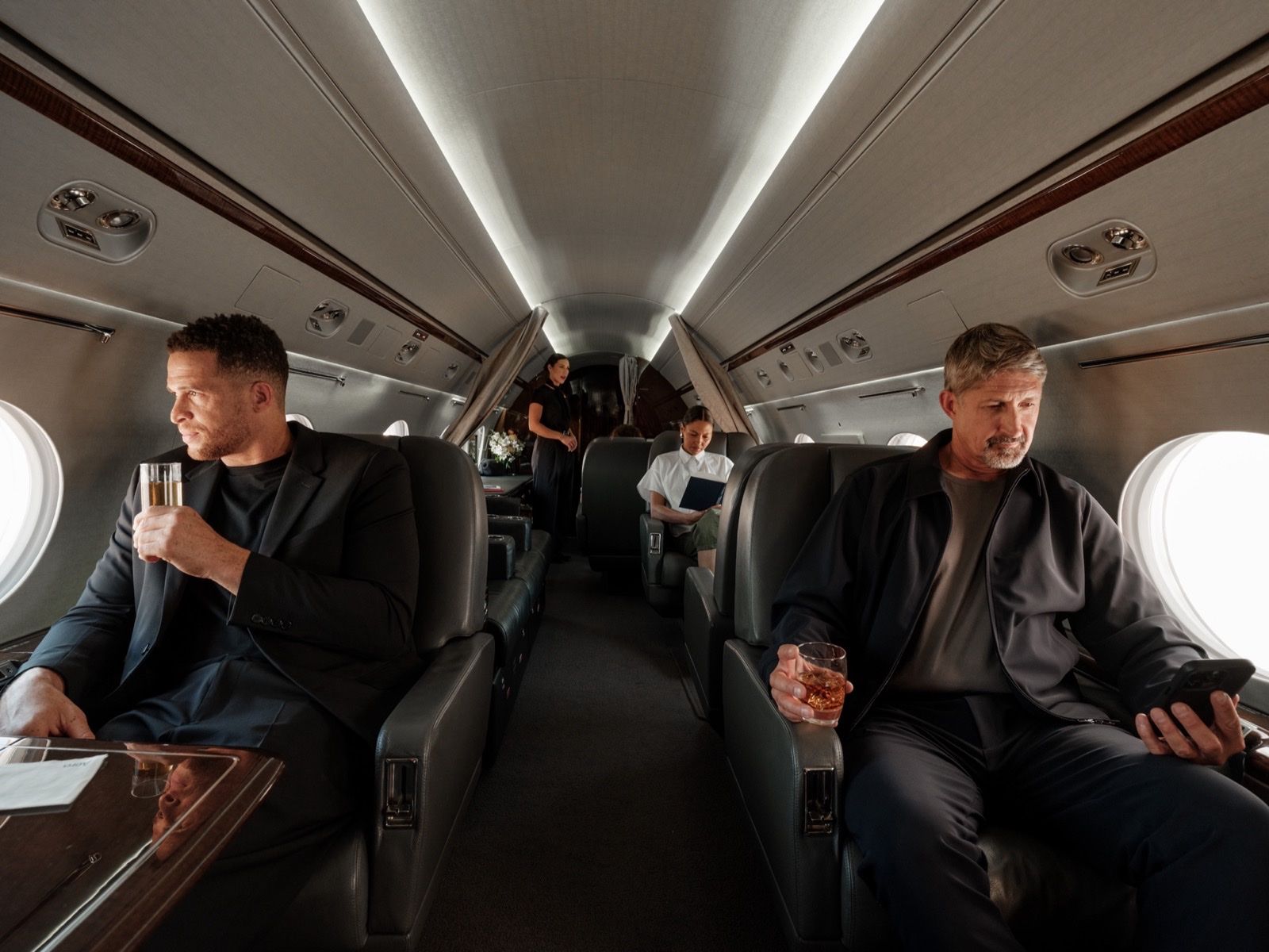 Passengers relaxing with drinks in a private jet cabin