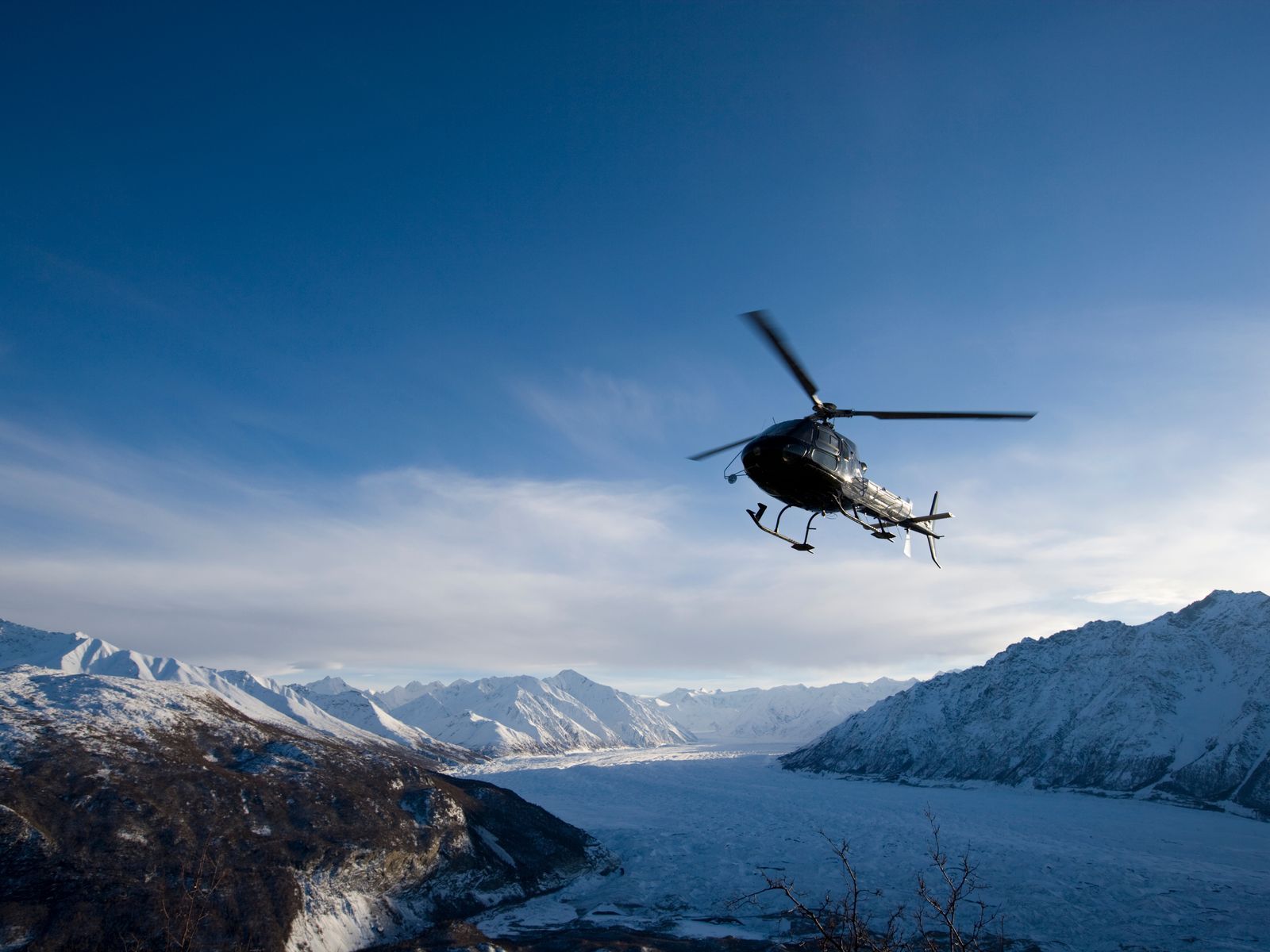 A helicopter flying over snow-covered alpine peaks
