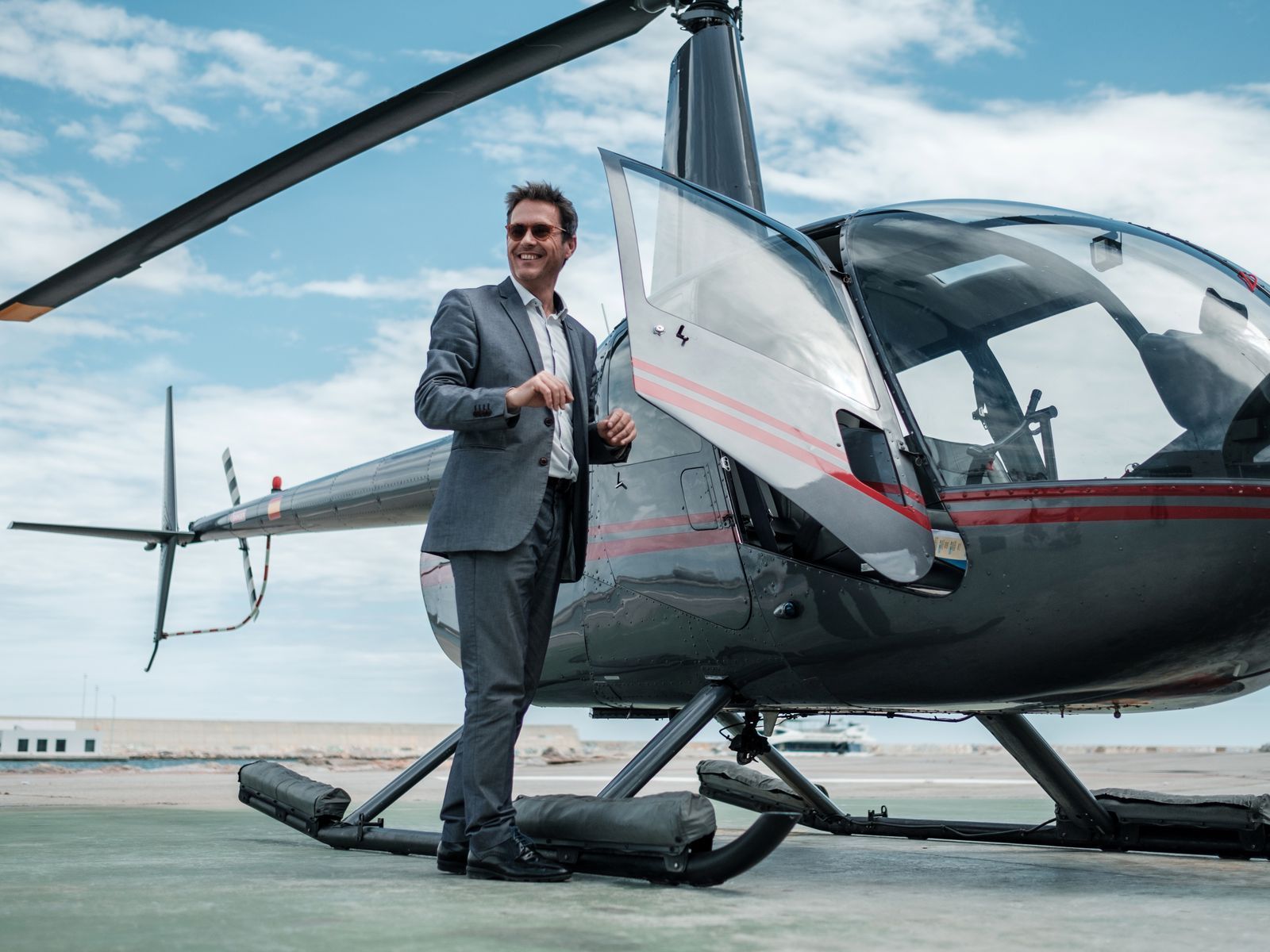 A businessman beside a private helicopter on the apron