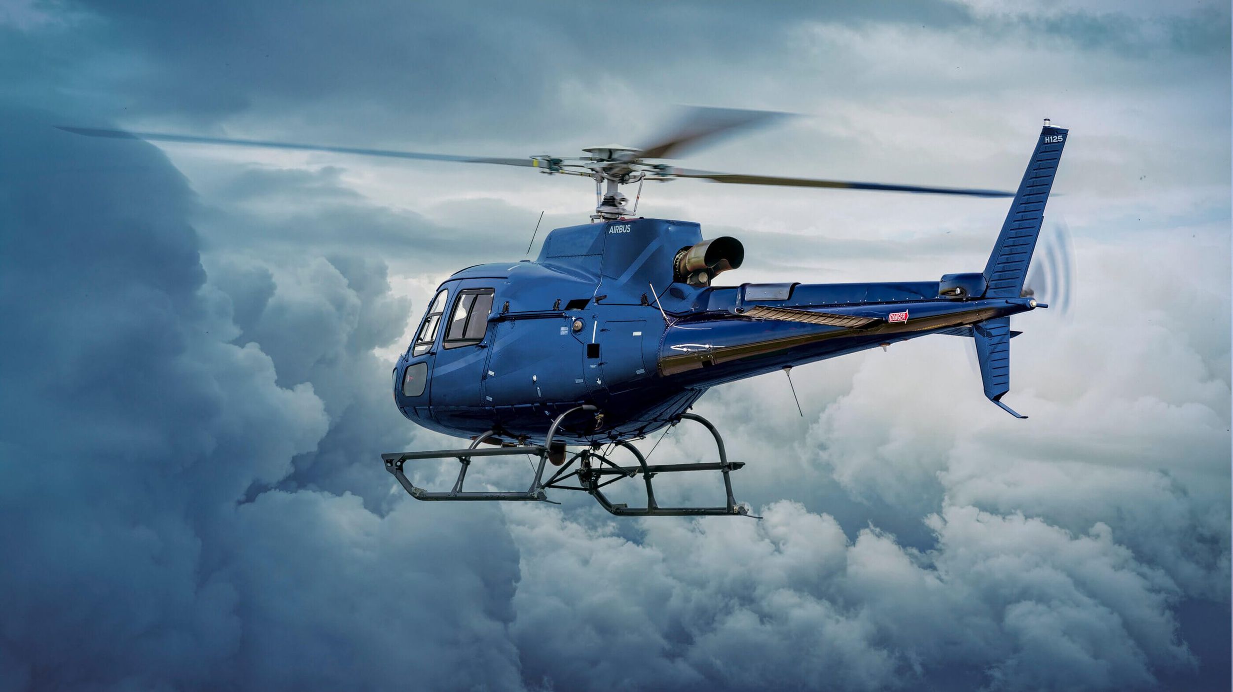 A single-engine helicopter in flight above the clouds