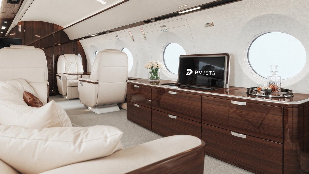 A private jet cabin interior with a vase of white roses and a screen displaying the PVJets logo