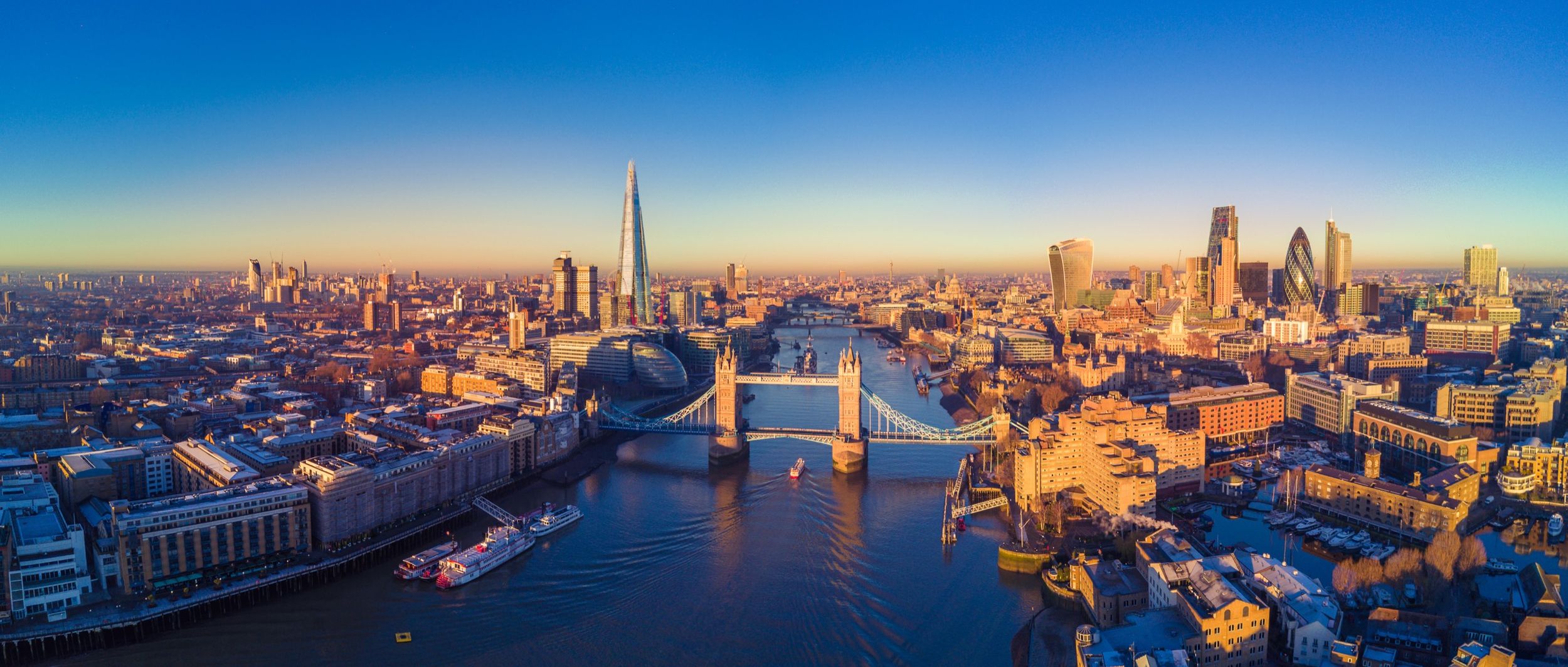 Aerial view of London at sunrise, with Tower Bridge, the River Thames and the City skyline