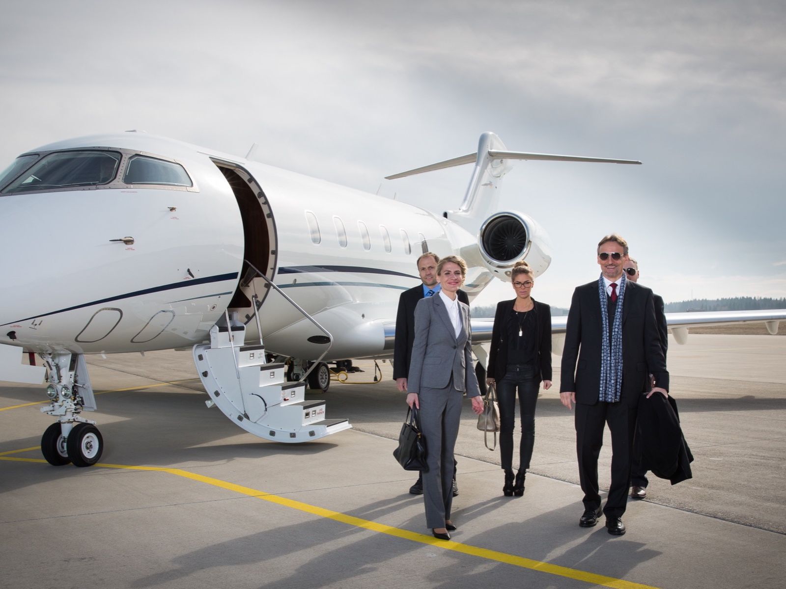 Business executives walking away from a private jet on the apron
