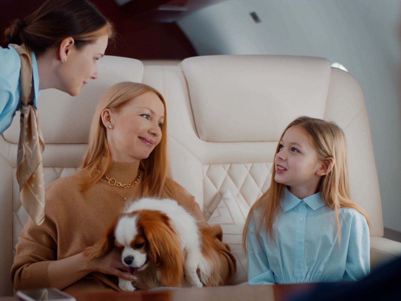 A family with their dog relaxing in a private jet cabin with a cabin attendant
