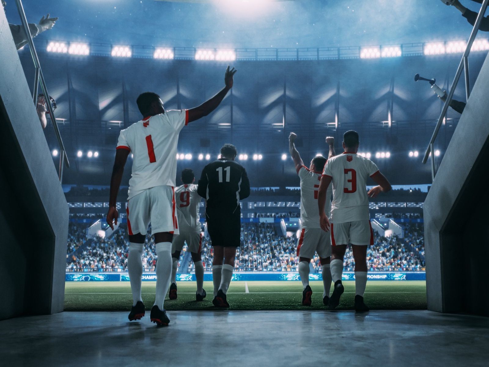 A sports team walking out onto the pitch of a floodlit stadium