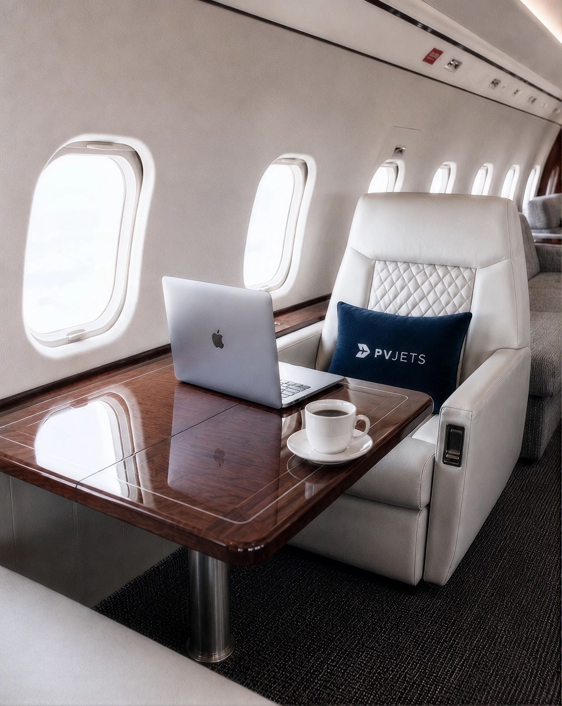 Laptop and coffee on a private jet cabin table with a PVJets cushion