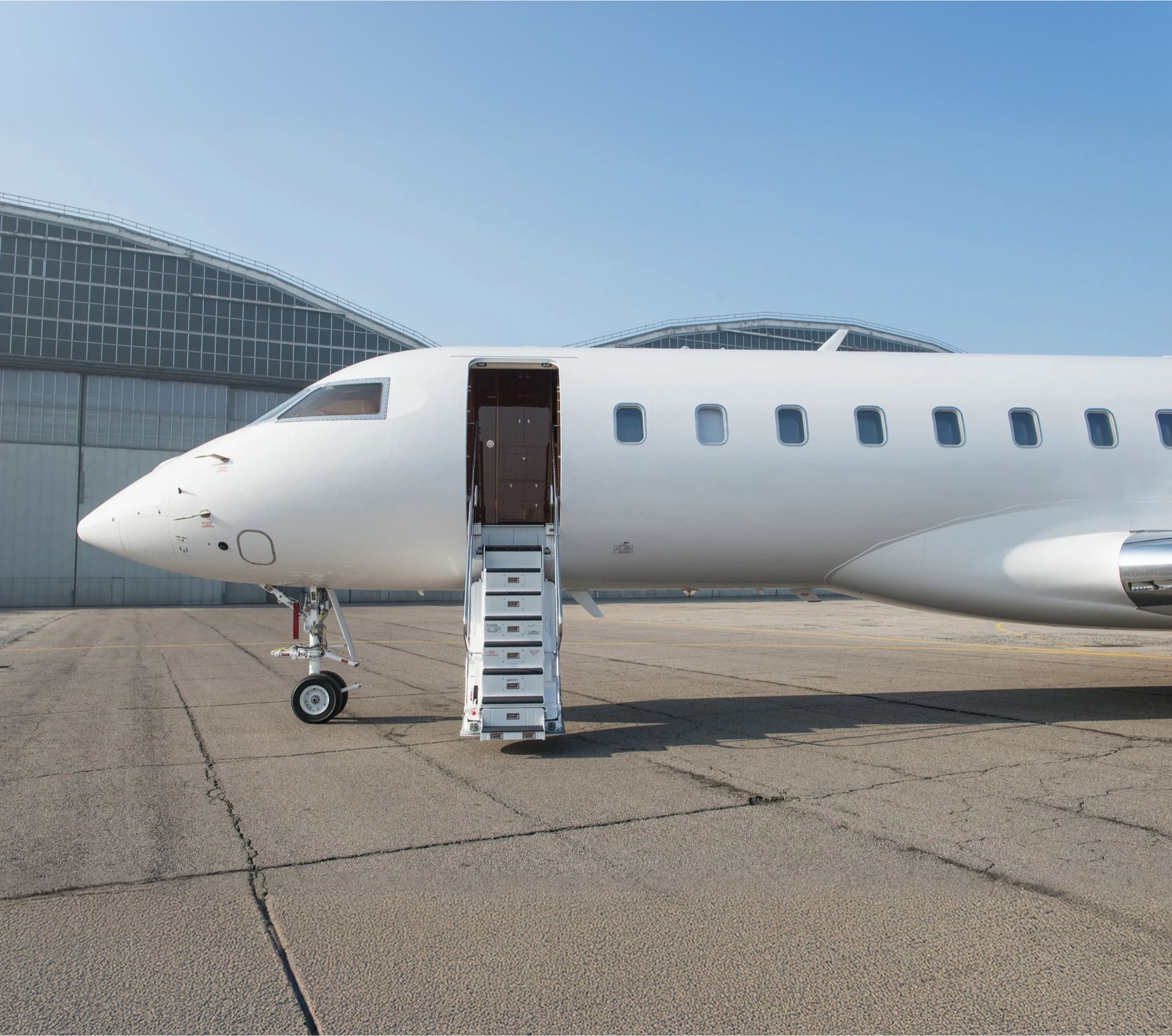 A private jet parked outside a hangar with its airstairs lowered